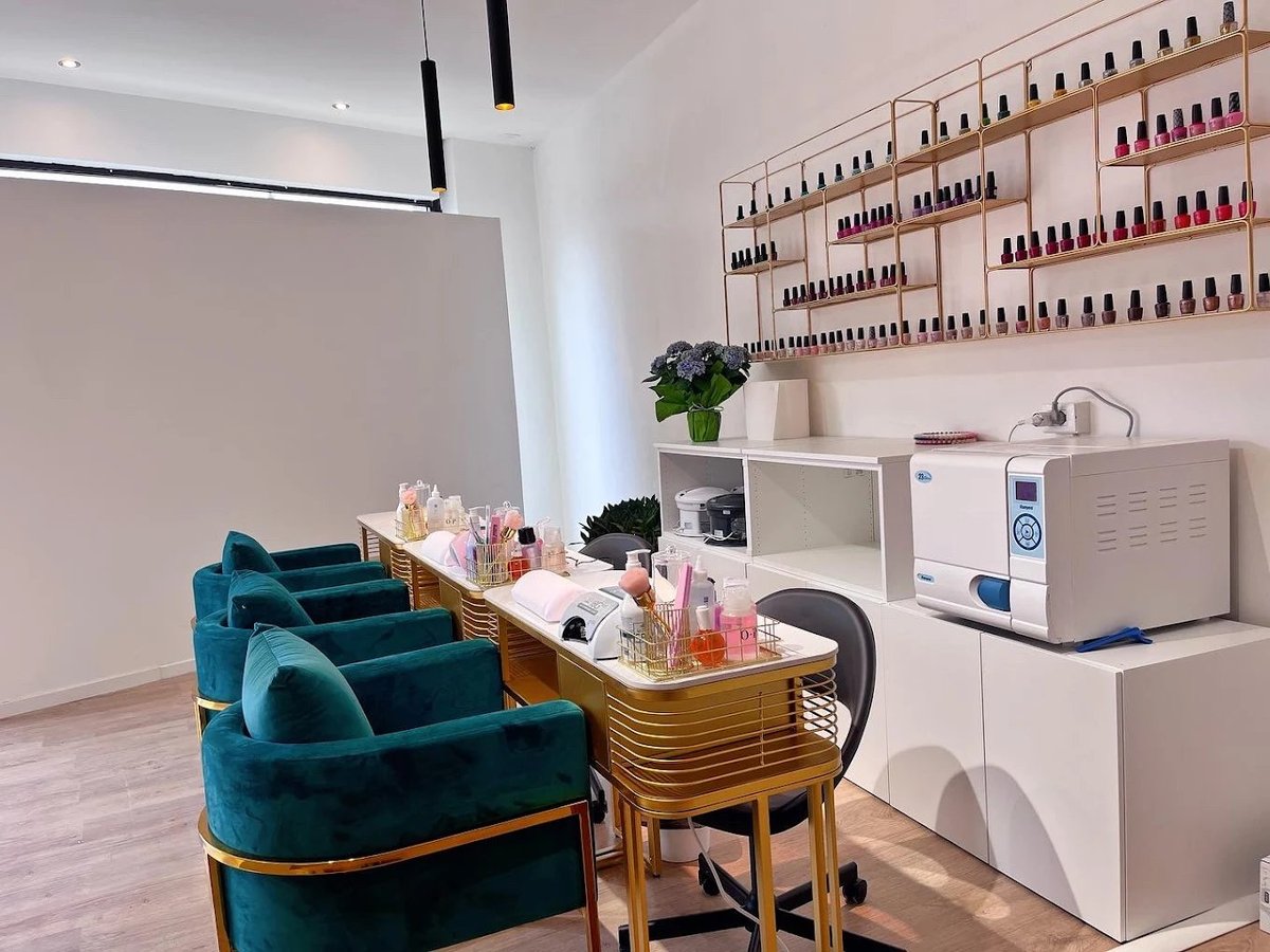 Interno moderno del salone Holly Nail SPA con sedie turchesi e muro di smalti